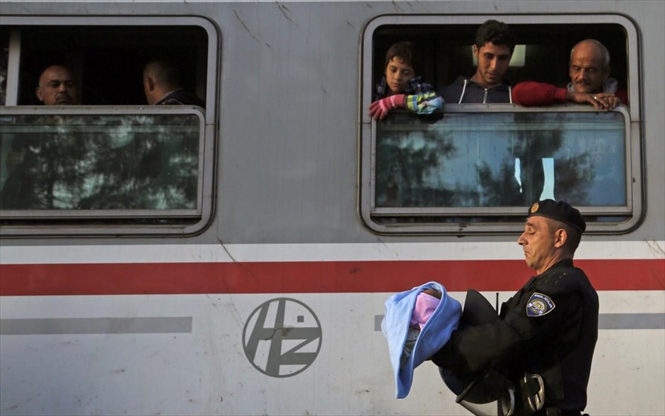 Μετανάστες στην Κροατία . Ένας αστυνομικός κρατάει ένα μωρό καθώς μετανάστες έχουν επιβιβαστεί στον σιδηροδρομικό σταθμό στο Tovarnik στην Κροατία.