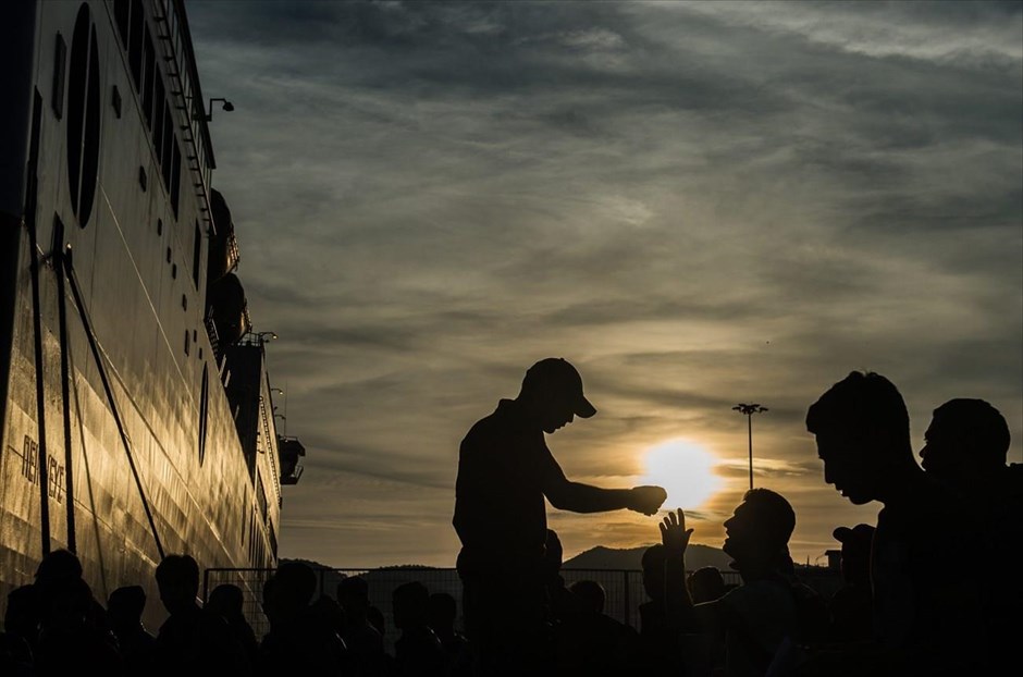Ετοιμασίες για ένα ακόμα ταξίδι. Αστυνομικός δίνει οδηγίες σε πρόσφυγες, που έχουν συγκεντρωθεί στο λιμάνι της Μυτιλήνης προκειμένου να επιβιβαστούν σε πλοίο που θα τους μεταφέρει στον Πειραιά. Οι περισσότεροι έχουν φτάσει στο νησί &nbsp;με σκάφη από τα παράλια της Τουρκίας,&nbsp;τις προηγούμενες ημέρες.&nbsp;