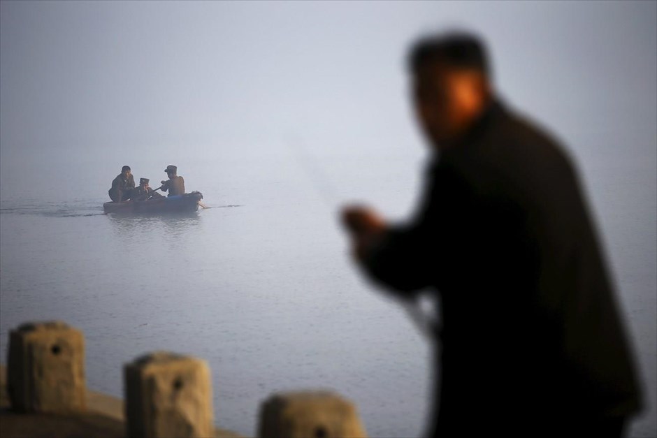 Βόρεια Κορέα - Επέτειος 70 χρόνων από την ίδρυση του Εργατικού Κόμματος Κορέας. Ένας άντρας ψαρεύει στον ποταμό Τεντόνγκ, ενώ πίσω του διακρίνονται στρατιώτες.