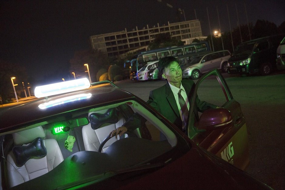 Βόρεια Κορέα - Επέτειος 70 χρόνων από την ίδρυση του Εργατικού Κόμματος Κορέας. Ο οδηγός ταξί Κιμ Μιονγκ Τσολ αφήνει τους πελάτες του στην είσοδο ενός ξενοδοχείου. Εδώ και δεκαετίες οι περισσότερες περιοχές της Βόρειας Κορέας εξυπηρετούνταν από έναν μικρό στόλο παλιών ταξί. Τα τελευταία χρόνια, ωστόσο, ο κλάδος σημειώνει άνθηση στην πρωτεύουσα.