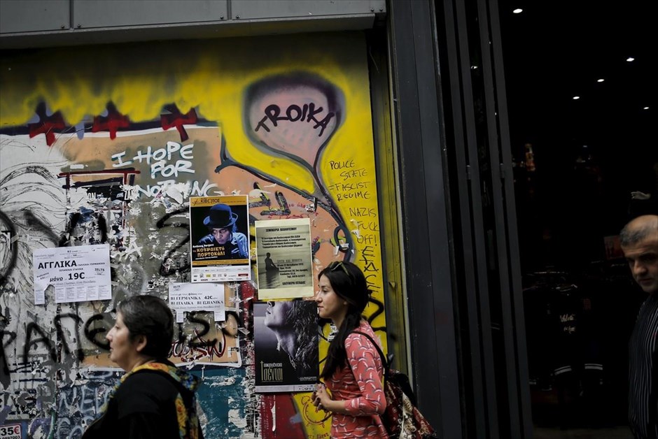 Στιγμιότυπο από το κέντρο της Αθήνας. Κόσμος περπατά μπροστά από τοίχο στον οποίο έχει ζωγραφιστεί η λέξη «τρόικα», στην Ερμου. Υπό διαρκή πίεση, αφενός από την πλευρά των δανειστών για τη λήψη των μέτρων που έχουν συμφωνηθεί,&nbsp;αφετέρου από τις κοινωνικές ομάδες που πλήττονται από τα νέα μέτρα, βρίσκεται η κυβέρνηση.&nbsp;Ενδεικτικό είναι το γεγονός&nbsp;ότι μέχρι τις γιορτές των Χριστουγέννων θα πρέπει η Ελλάδα να έχει συμφωνήσει σε όλα τα ανοικτά ζητήματα, όπως για παράδειγμα το ασφαλιστικό, τα «κόκκινα δάνεια», τα κλειστά επαγγέλματα, τα νέα δημοσιονομικά μέτρα, τη φορολογική μεταρρύθμιση, τις αλλαγές στα εργασιακά, τις ιδιωτικοποιήσεις και το νέο Ταμείο Αποκρατικοποίησεων.