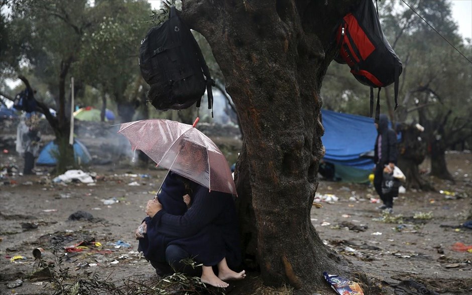 Λέσβος: Έφτασαν πάνω από 5000 πρόσφυγες και μετανάστες το τελευταίο 24ωρο. Πρόσφυγας προσπαθεί να προστατέψει το παιδί του από την καταιγίδα ενώ περιμένει να έρθει η σειρά τους σε Κέντρο καταγραφής της Λέσβου.