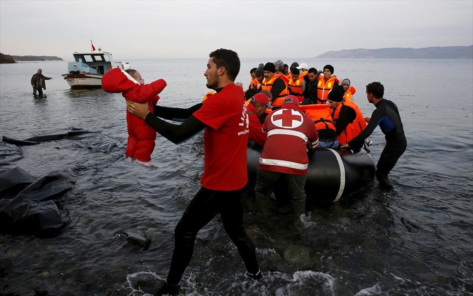 Άφιξη προσφύγων στη Λέσβο. Εθελοντές του Ερυθρού Σταυρού βοηθούν Σύρους πρόσφυγες να αποβιβαστούν από την υπερπλήρη βάρκα που τους μετέφερε σε ακτή της Λέσβου. Από τους 660.000 πρόσφυγες και μετανάστες που έχουν φτάσει στην Ελλάδα φέτος, περισσότεροι από τους μισούς έχουν αποβιβαστεί στο νησί της Λέσβου. Μέχρι στιγμής, περίπου 3.460 άνθρωποι έχασαν τη ζωή τους στην προσπάθειά τους να διασχίσουν τη Μεσόγειο το 2015.