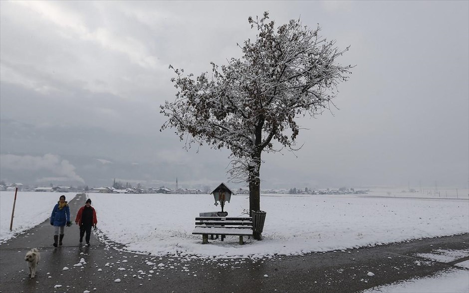 Χιόνια στην Αυστρία. Κόσμος κάνει περίπατο σ’ ένα χωράφι που έχει καλυφθεί από χιόνι στον χωριό Absam, στη δυτική Αυστρία.
