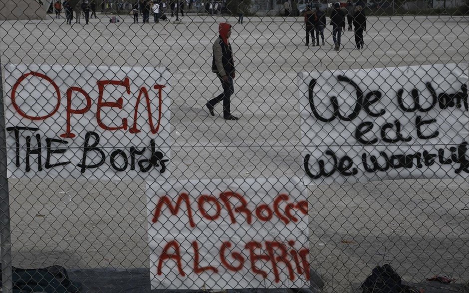 Μετανάστες στο γήπεδο του Τάε Κβο Ντο . Μετανάστες περπατούν πίσω από πανό, μέσα στον προαύλιο χώρο του Τάε Κβο Ντο, στο Παλαιό Φάληρο.