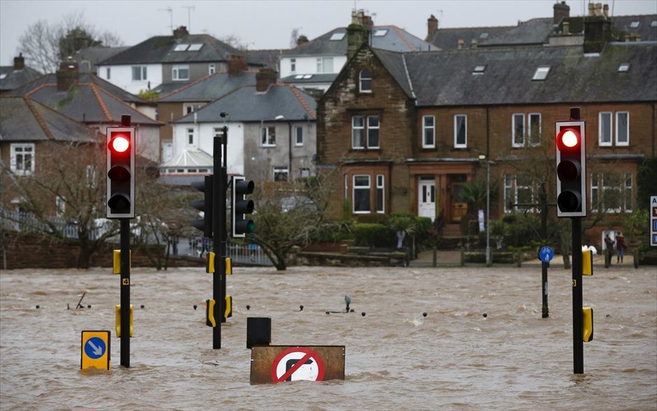 Πλημμύρες στη Σκωτία. Πλημμυρισμένος δρόμος στο Ντάμφρις της Σκωτίας. Καταρρακτώδεις βροχές και θυελλώδεις άνεμοι σαρώνουν το βόρειο τμήμα της Αγγλίας, τη Σκωτία και τη Βόρεια Ιρλανδία με αποτέλεσμα να βυθιστούν στο σκοτάδι χιλιάδες κατοικίες και πολλοί πολίτες να αναγκαστούν να απομακρυνθούν με βάρκες από τα πλημμυρισμένα σπίτια τους, στην τρίτη μεγάλη καταιγίδα που πλήττει την περιοχή μέσα σε διάστημα μόλις ενός μήνα.