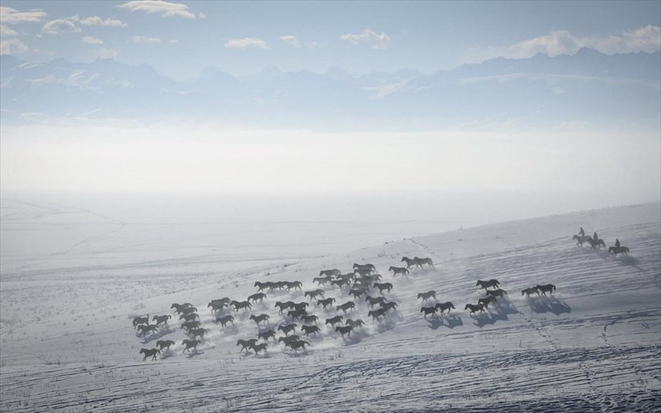 Στιγμιότυπο από το Σιντζιάνγκ . Βοσκοί ιππεύουν τα άλογά τους σ’ ένα χιονισμένο χωράφι στην Αυτόνομη Περιοχή των Ουιγούρων του Σιντζιάνγκ, στην Κίνα.  