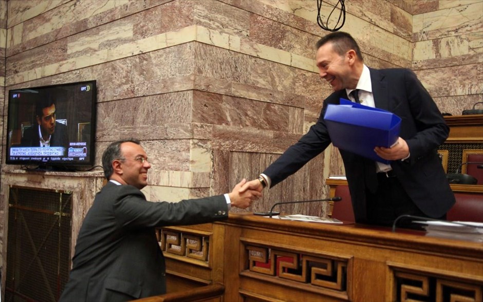 Γρήγορη ολοκλήρωση της αξιολόγησης ζητεί ο Γ. Στουρνάρας. Ο διοικητής της Τράπεζας της Ελλάδος, Γιάννης Στουρνάρας, ανταλλάσσει χειραψία με τον πρώην αναπληρωτή υπουργό Οικονομικών Χρήστο Σταϊκούρα στην αιθουσα Γερουσίας της Βουλής, ενώ σε οθόνη πίσω τους διακρίνεται ο Πρωθυπουργός, Αλέξης Τσίπρας, να μιλά στο υπουργικό συμβούλιο. Ο κ. Στουρνάρας ενημέρωσε την επιτροπή οικονομικών υποθέσεων της Βουλής για την Ενδιάμεση Έκθεση της Τράπεζας της Ελλάδος για τη Νομισματική Πολιτική 2015. Την ίδια στιγμή ο Πρωθυπουργός κατά την εισήγησή του άφησε «παράθυρο» για βελτιώσεις στο σχέδιο για το ασφαλιστικό, υπογραμμίζοντας πάντως ότι απαραίτητη προϋπόθεση είναι να καθίσουν οι επιστημονικοί φορείς και οι αγρότες στο τραπέζι του διαλόγου.