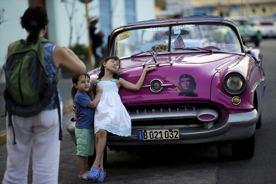 Κούβα - Αβάνα. Τουρίστες φωτογραφίζονται μπροστά από αυτοκίνητο που φέρει τη μορφή του Τσε Γκεβάρα.