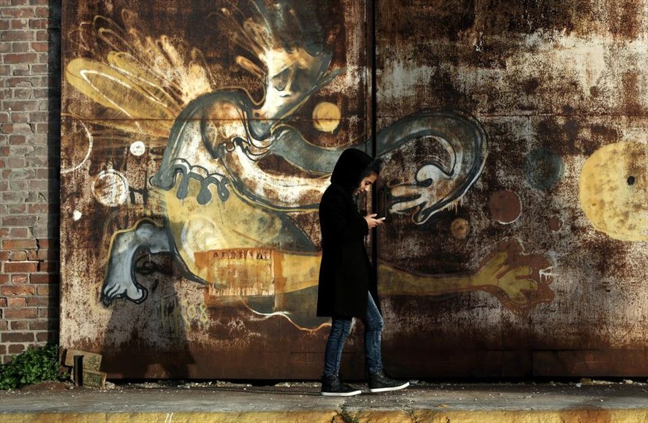 Πάνω από 5.000 άτομα στις εγκαταστάσεις του ΟΛΠ. Μια γυναίκα περπατά μπροστά από γκράφιτι στο λιμάνι του Πειραιά. Εκτός ελέγχου τείνει η κατάσταση στο σημείο, καθώς ο αριθμός των προσφύγων - μεταναστών, οι οποίοι έχουν βρει προσωρινό κατάλυμα στις εγκαταστάσεις του ΟΛΠ, υπερβαίνει τις 5.000.