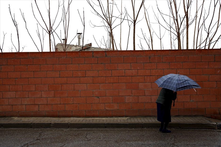 Αναζητώντας τον Δον Κιχώτη . Μια ηλικιωμένη γυναίκα περπατά υπό βροχή, σε δρόμο της πόλης Κονσουέγκρα.