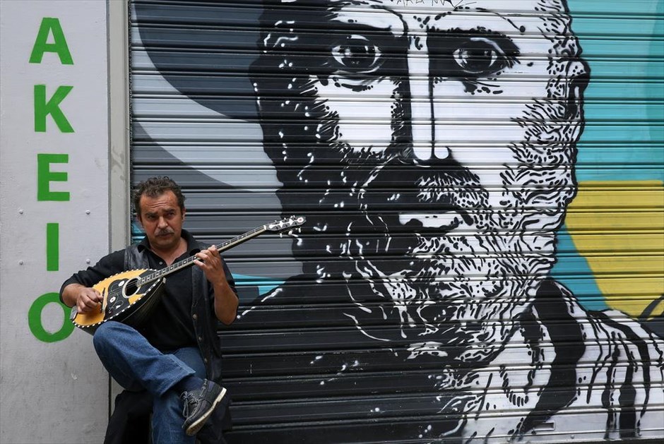 Στιγμιότυπο από το κέντρο της Αθήνας. Ένας άντρας παίζει μπουζούκι έξω από ένα κλειστό μαγαζί στου Ψυρρή.&nbsp;