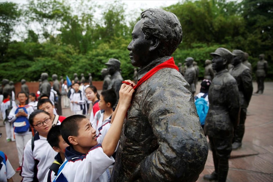 Κίνα: 50η επέτειος της Πολιτιστικής Επανάστασης. Μαθητής τυλίγει ένα κόκκινο μαντήλι στο άγαλμα του Μάο, σε πλατεία της πόλης Ανρέν, όπου έχουν τοποθετηθεί αγάλματα των ηρώων του πολέμου με την Ιαπωνία.