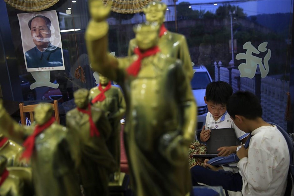 Κίνα: 50η επέτειος της Πολιτιστικής Επανάστασης. Μαθητές παίζουν με τα τάμπλετ τους σε εστιατόριο της γενέτειρας του Μάο Τσετούνγκ, Σαοσάν, το οποίο είναι διακοσμημένο με αγάλματα του ιδρυτή της Λαϊκής Δημοκρατίας της Κίνας. 