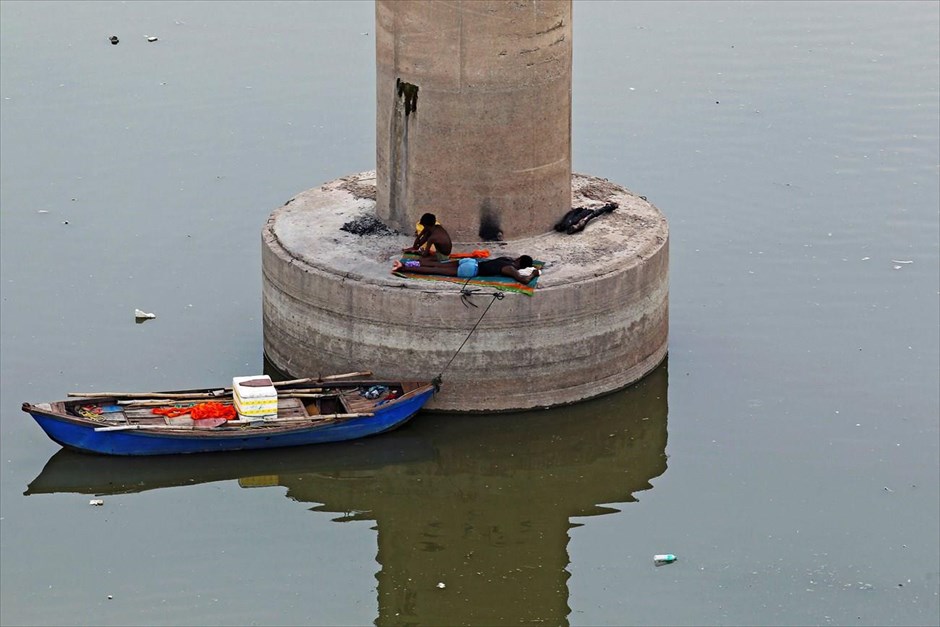 Καθημερινή ζωή στην Ινδία. Δύο άντρες ξεκουράζονται πάνω σε πυλώνα γέφυρας στο ποταμό Γάγγη, στο Αλλαχαμπάντ της Ινδίας