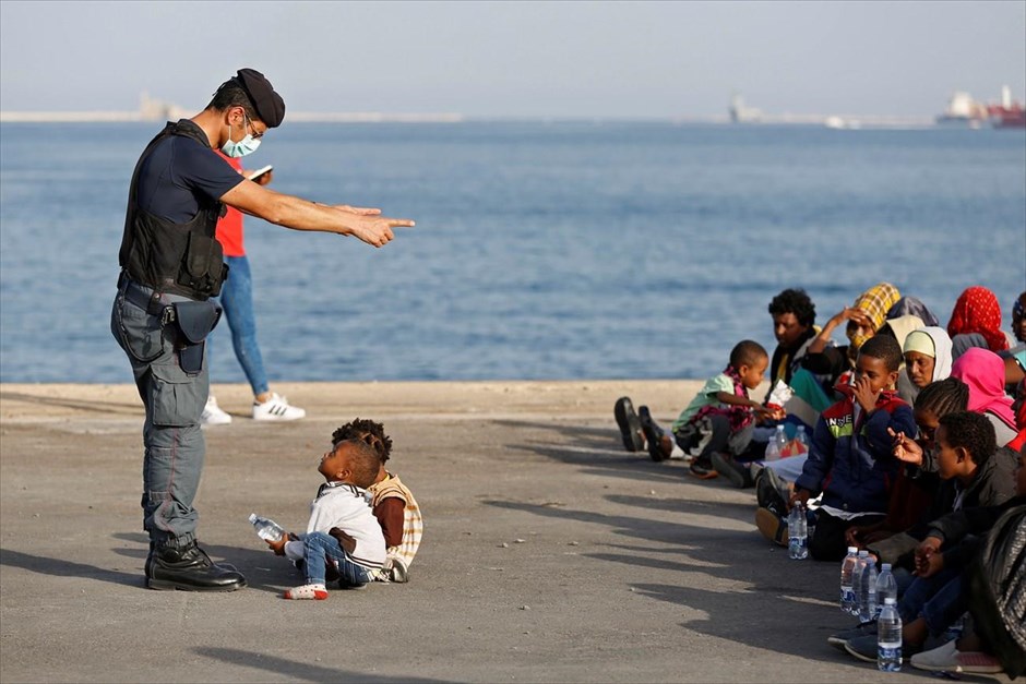 Μετανάστες στο λιμάνι της Σικελίας . Αστυνομικός μιλά σε δύο παιδάκια, κατά τη διάρκεια αποβίβασης μεταναστών, που διασώθηκαν στη Μεσόγειο, στο λιμάνι της Αουγκούστα της Σικελίας.