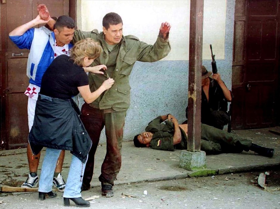 Κολομβία: 52 χρόνια ένοπλης σύγκρουσης κυβέρνησης και ανταρτών FARC. Δύο πολίτες από την πόλη Ντολόρες, περίπου 180 χιλιόμετρα βορειοανατολικά της Μπογκοτά, ψάχνουν τα ρούχα ενός αστυνομικού για κρυμμένα όπλα με εντολή των ανταρτών της οργάνωσης FARC, κατά τη διάρκεια επιδρομής στην πόλη (17 Νοεμβρίου 1999).