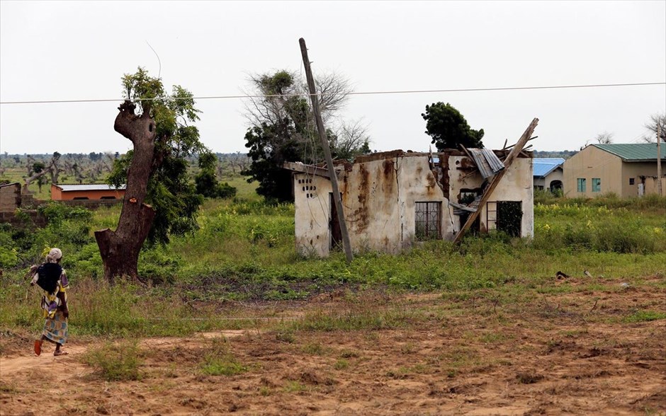 Νιγηρία - Μπόκο Χαράμ. Μια γυναίκα περπατάει προς σπίτι που έχει υποστεί ζημιές από τα πυρά μαχητών της Μπόκο Χαράμ.