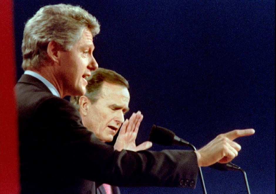 Εκλογές ΗΠΑ - Debate. Ο υποψήφιος των Δημοκρατικών και κυβερνήτης Μπιλ Κλίντον διατυπώνει ένα επιχείρημα, καθώς ο Ρεπουμπλικανός αντίπαλός του και πρόεδρος των ΗΠΑ Τζορτζ Μπους διαφωνεί, κατά τη διάρκεια της τρίτης και τελικής τους τηλεοπτικής αναμέτρησης στο Ήστ Λάνσινγκ, στο Μίσιγκαν (19 Οκτωβρίου 1992).