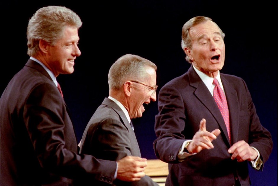 Εκλογές ΗΠΑ - Debate. Ο υποψήφιος των Δημοκρατικών και κυβερνήτης του Αρκάνσας Μπιλ Κλίντον, ο ανεξάρτητος υποψήφιος Ρος Περό (στο κέντρο) και ο πρόεδρος των ΗΠΑ Τζορτζ Μπους, κατά τη διάρκεια της τρίτης και τελικής τους τηλεοπτικής αναμέτρησης στο Ήστ Λάνσινγκ, στο Μίσιγκαν. Στη μνήμη όσων παρακολούθησαν έχει χαραχτεί η επιμονή του Μπους να κοιτάει το ρολόι του, δίνοντας την εντύπωση πως δεν πολυ-ενδιαφέρεται για την αναμέτρηση (19 Οκτωβρίου 1992).