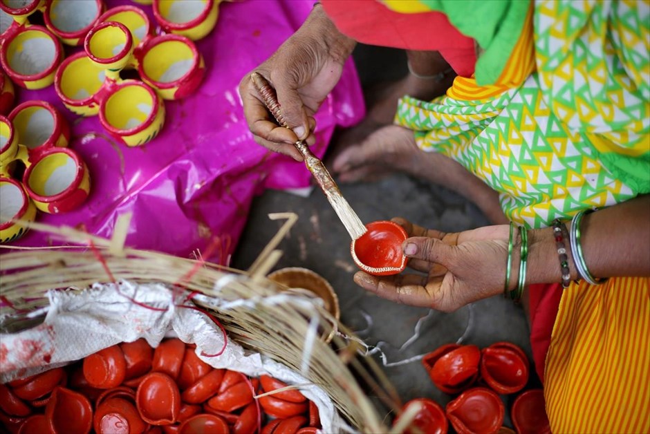 Προετοιμασίες για το φεστιβάλ του φωτός στην Ινδία. Μια γυναίκα βάφει πήλινα δοχεία, που χρησιμοποιούνται στο πλαίσιο του φεστιβάλ φωτός Ντιβάλι για τον φωτισμό των σπιτιών, σε εργαστήριο στην Καλκούτα.