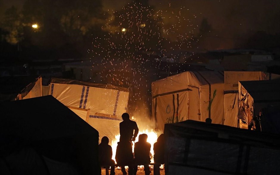 Εκκένωση Καλαί. Μετανάστες ζεσταίνονται γύρω από τη φωτιά κατά την πρώτη μέρα εκκένωσης του Καλαί.