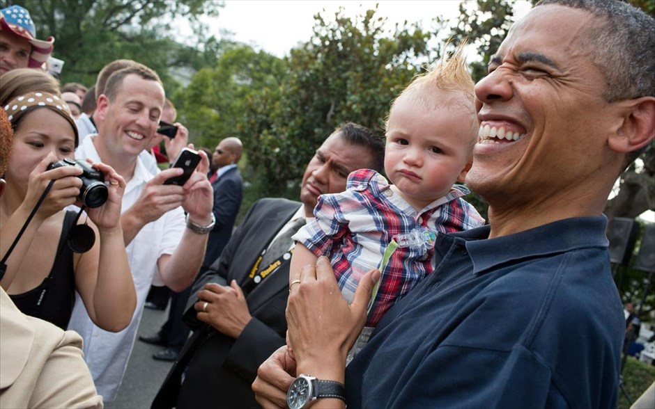 Μπαράκ Ομπάμα - Τα αγαπημένα καρέ του φωτογράφου του Ομπάμα. Ο Μπαράκ Ομπάμα κρατά στην αγκαλιά του ένα μωρό, ενώ υποδέχεται καλεσμένους, κατά τη διάρκεια εορτασμού της Ημέρας της Ανεξαρτησίας στον κήπο του Λευκού Οίκου (4 Ιουλίου 2012).