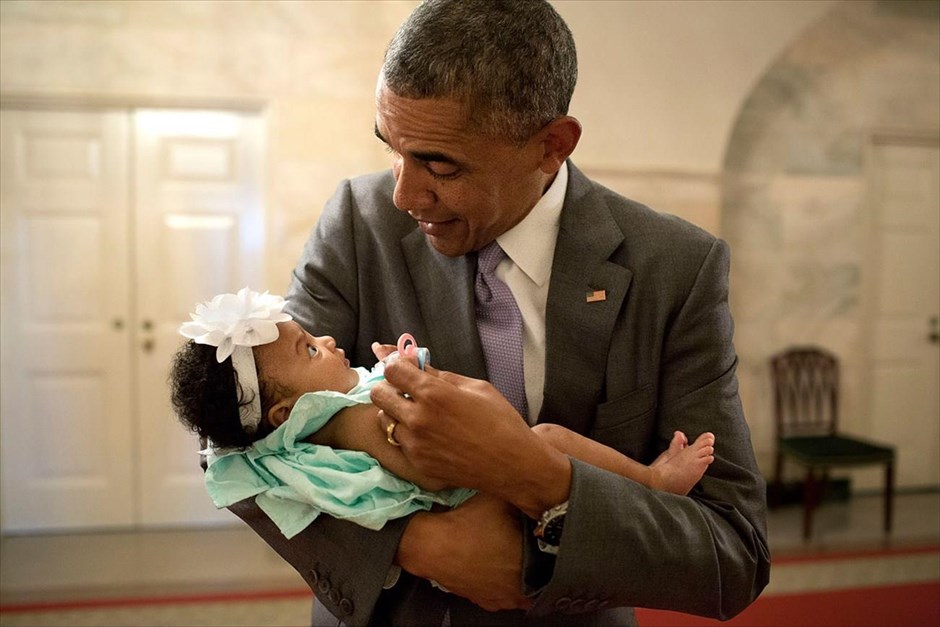 Μπαράκ Ομπάμα - Τα αγαπημένα καρέ του φωτογράφου του Ομπάμα. Ο πρόεδρος Μπαράκ Ομπάμα κρατά στην αγκαλιά του την κόρη των πρώην υπαλλήλων του Λευκού Οίκου Ντάριεν Πέιτζ και Λόντον Ρέικστρο, στο Λευκό Οίκο (1 Ιουλίου 2014).