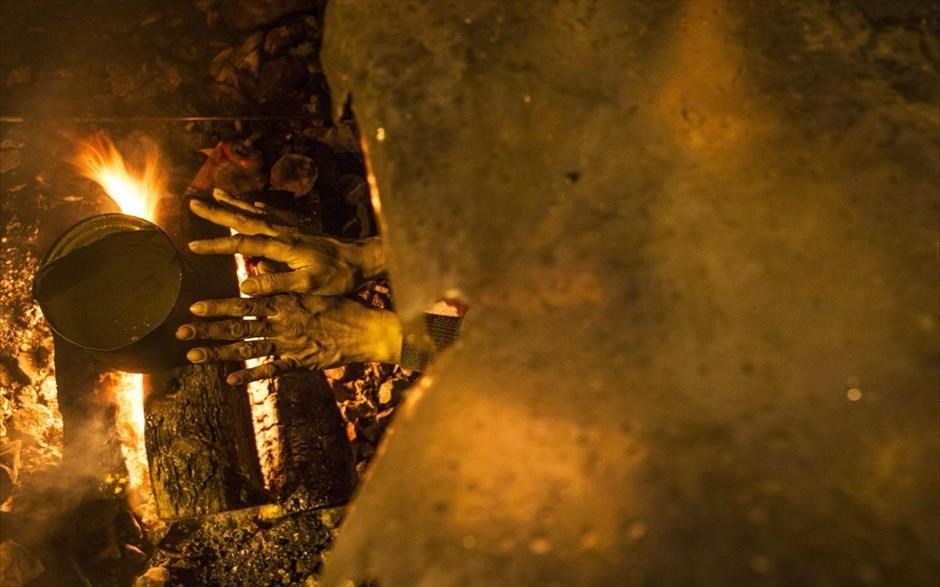 POY2016. Μετανάστρια ζεσταίνει τα χέρια της στη φωτιά στον προσφυγικό καταυλισμό της Ειδομένης (11 Απριλίου).