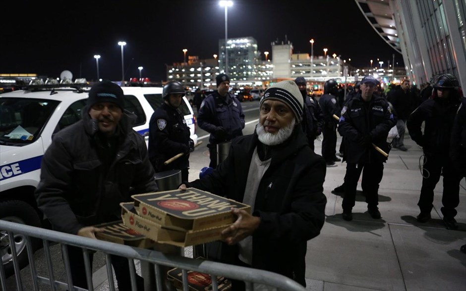 ΗΠΑ - Τραμπ - αεροδρόμιο - περιορισμοί εισόδου στις ΗΠΑ - διάταγμα. Ένας άντρας μοιράζει πίτσα στους διαδηλωτές, έξω από το διεθνές αεροδρόμιο Τζον Φ. Κένεντι στη Νέα Υόρκη.