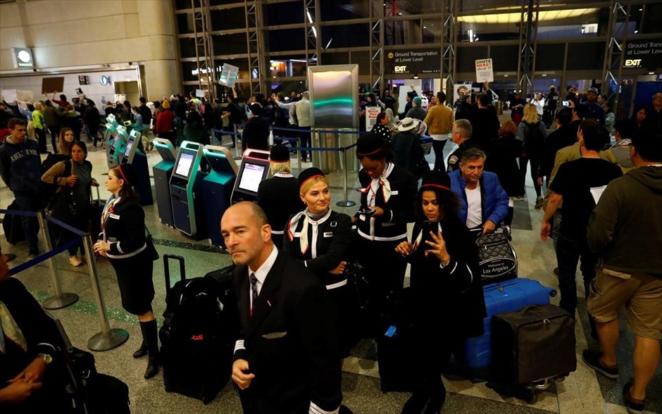 ΗΠΑ - Τραμπ - αεροδρόμιο - περιορισμοί εισόδου στις ΗΠΑ - διάταγμα. Πλήρωμα αεροσκάφους παρακολουθεί τον κόσμο που διαδηλώνει εναντίον του διατάγματος Τραμπ, στο διεθνές αεροδρόμιο του Λος Άντζελες.