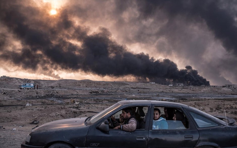 World Press Photo - General News - 2. Ο φωτογράφος των New York Times Sergey Ponomarev κέρδισε το δεύτερο βραβείο στην κατηγορία «General News, Stories». Στη φωτογραφία που λήφθηκε στις 12 Νοεμβρίου 2016, μία οικογένεια προσπαθεί να ξεφύγει από τις μάχες στη Μοσούλη, τη δεύτερη μεγαλύτερη πόλη του Ιράκ, ενώ πετρελαιοπηγές έχουν πάρει φωτιά.