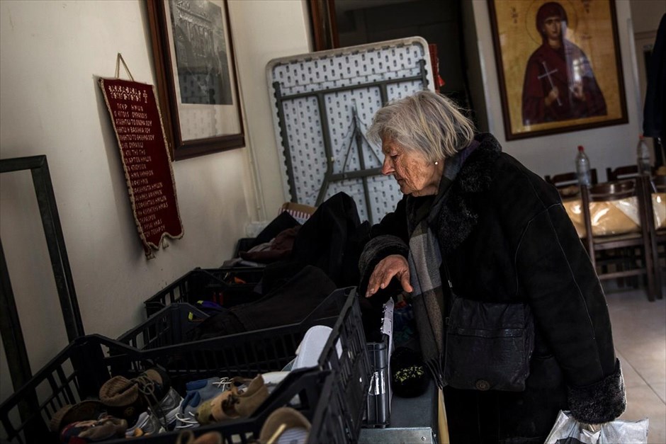 Ελλάδα - φτώχεια . Μια γυναίκα κοιτά τα ρούχα που έχουν δωρίσει πολίτες στην Εκκλησία.