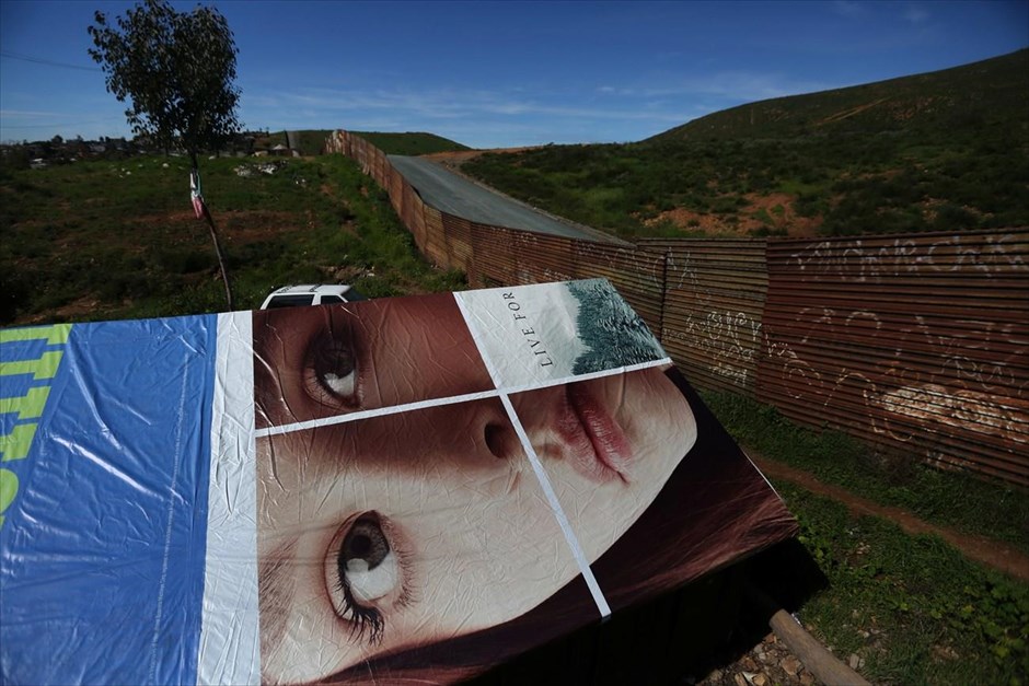 Μεξικό: Στη σκιά του φράχτη. Διαφημιστική αφίσα χρησιμοποιείται αντί οροφής σε κατοικία κοντά στα σύνορα Μεξικού - ΗΠΑ.