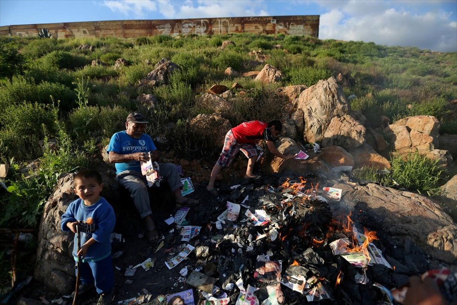 Μεξικό: Στη σκιά του φράχτη. Μια οικογένεια καίει απορρίμματα.