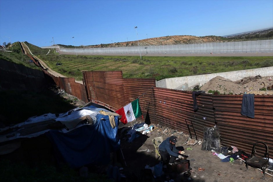 Μεξικό: Στη σκιά του φράχτη. Ο 27χρονος Κάρλος, που όπως λέει απελάθηκε από τις ΗΠΑ, ζεσταίνει τορτίγιες στο σπίτι του δίπλα στα σύνορα.