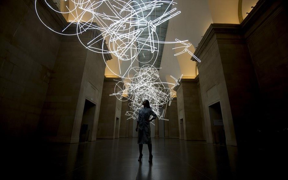Καλλιτεχνική εγκατάσταση στην Tate Britain. Υπάλληλος γκαλερί κοιτά την καλλιτεχνική εγκατάσταση φωτός με τίτλο «Φόρμες στο Χώρο.. με Φως (στο Χρόνο) - Forms in Space...by Light (in Time)» του Ουαλού καλλιτέχνη Cerith Wyn Evans, στο μουσείο τέχνης Tate Britain στο Λονδίνο. Η εγκατάσταση είναι φτιαγμένη από περίπου 2 χιλιόμετρα φωτισμού νέον και δημιουργήθηκε ως έργο για το κέντρο του μουσείου της Tate για το 2017.