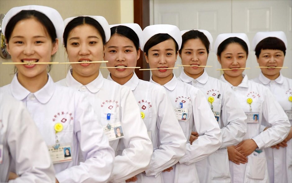 Εξάσκηση για σωστό χαμόγελο στην Κίνα. Νοσοκόμες κάνουν εξάσκηση με ξυλάκια για να χαμογελούν σωστά, σε ένα νοσοκομείο στη Χαντάν, στην επαρχία Χεμπέι.