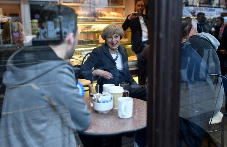 Βρετανία: Μειώνεται η διαφορά Συντηρητικών - Εργατικών. H πρωθυπουργός της Βρετανίας Τερέζα Μέι συνομιλεί με κόσμο σε ένα φούρνο, κατά τη διάρκεια της επίσκεψής της στο Φλίτγουντ, στο πλαίσιο της προεκλογικής της εκστρατείας. Οι βρετανικές εκλογές εξελίσσονται σε θρίλερ, καθώς σύμφωνα με τις δημοσκοπήσεις, η διαφορά Συντηρητικών - Εργατικών έχει πέσει σε μία μονάδα. Η εταιρεία YuGov επαναλαμβάνει σε νέα πρόβλεψή της ότι η νέα «σιδηρά κυρία» της Βρετανίας δεν θα καταφέρει να έχει απόλυτη πλειοψηφία εδρών προκειμένου να σχηματίσει αυτοδύναμη ισχυρή κυβέρνηση προκειμένου να αναλάβει το τιτάνιο έργο των διαπραγματεύσεων του Brexit.