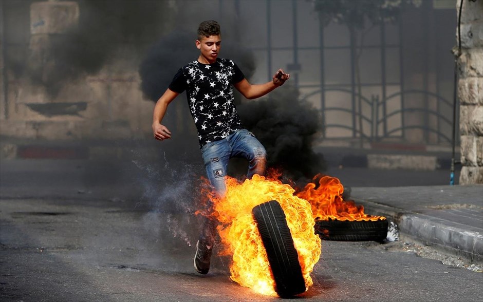 Επεισόδια στη Χεβρώνα. Ένας Παλαιστίνιος σπρώχνει ένα φλεγόμενο λάστιχο κατά τη διάρκεια συγκρούσεων με ισραηλινές δυνάμεις ασφαλείας, στην Χεβρώνα.