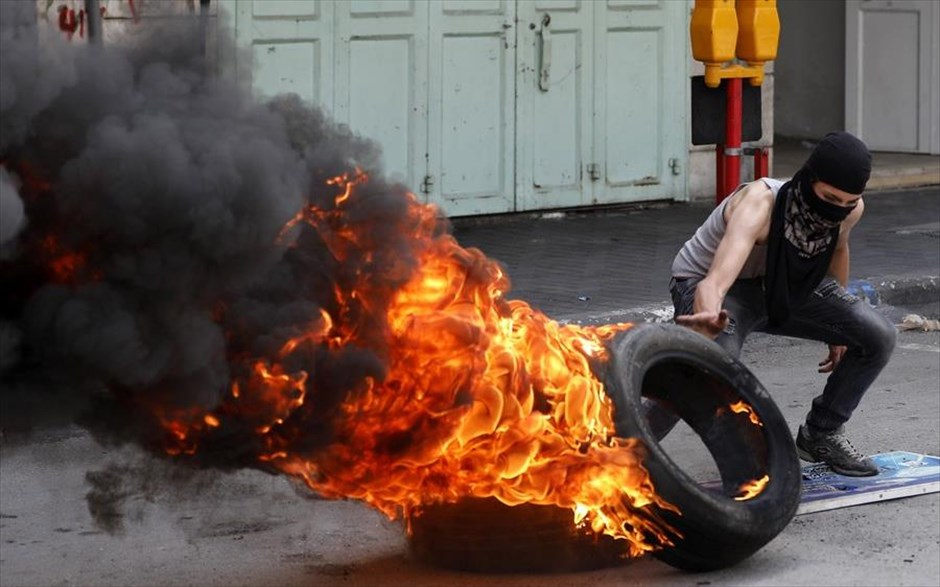 Συγκρούσεις στη Δυτική Όχθη . Παλαιστίνιος τοποθετεί ελαστικό που καίγεται σε δρόμο της Χεβρώνας, στη Δυτική Όχθη, με σκοπό να εμποδίσει τη διεύλευση. Χιλιάδες Παλαιστίνιοι διαδήλωσαν χθες και για τρίτη συναπτή Παρασκευή σε σημεία των συνόρων Λωρίδας της Γάζας - Ισραήλ, στο πλαίσιο της διαμαρτυρίας έξι εβδομάδων με τίτλο «Μεγάλη Πορεία Επιστροφής».