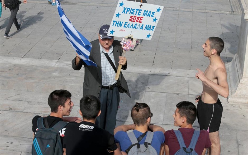 Πρωτομαγιά με επίκληση στα θεία . Άνδρας με πλακάτ στο Σύνταγμα, στην Αθήνα, πριν από την συγκέντρωση που διοργανώθηκε από το Πανεργατικό Αγωνιστικό Μέτωπο (ΠΑΜΕ).&nbsp;
