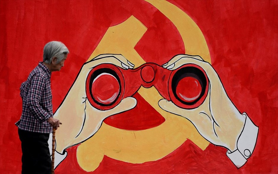 Κομμουνιστική τοιχογραφία στην Κίνα. Ηλικιωμένη περνάει μπροστά από τοιχογραφία που εικονίζει το έμβλημα του Κομμουνιστικού Κόμματος της Κίνας σε δρόμο στη Σαγκάη.