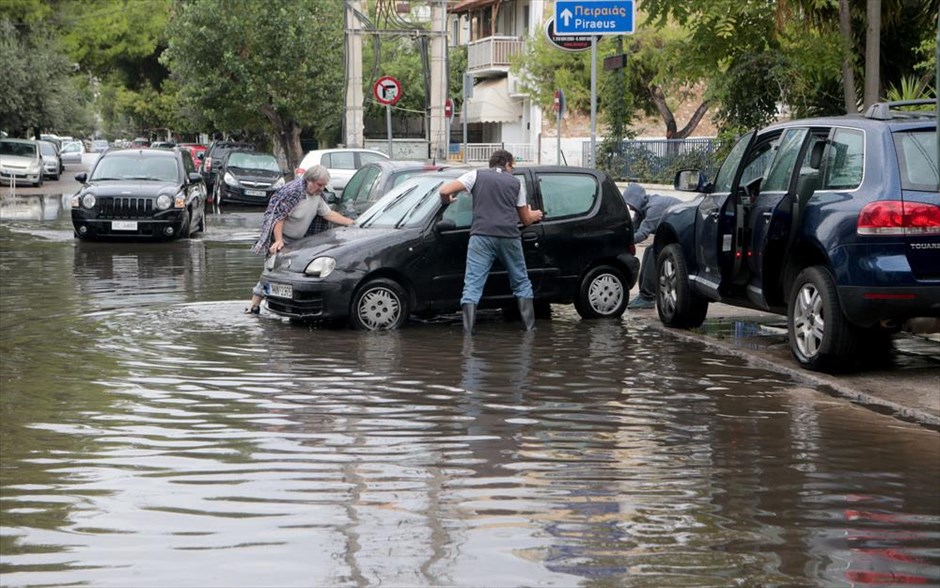 Κακοκαιρία- καιρός- άνεμοι- Αθήνα- πλημμυρισμένοι δρόμοι. Ανδρες προσπαθούν να μετακινήσουν αυτοκίνητο από πλημμυρισμένο δρόμο πισω από το Ίδρυμα Σταύρος Νιάρχος.