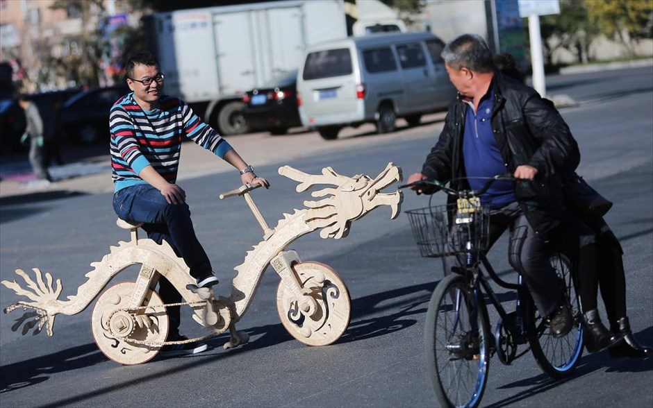 Βόλτα με δράκο στην Κίνα . Ένας άνδρας οδηγάει ποδήλατο σε σχήμα δράκου φταιγμένο στο χέρι από ξυλάκια παγωτού σε δρόμο στην πόλη Τιέλινγκ της Κίνας.  