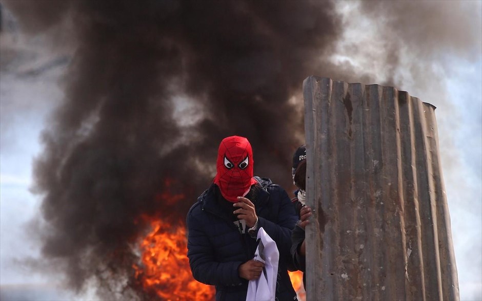 Ένταση στην Ινδία. Διαδηλωτής με μάσκα διακρίνεται μπροστά από λάστιχα που καίγονται κατά τη διάρκεια επεισοδίων στη Σριναγκάρ της Ινδίας. 