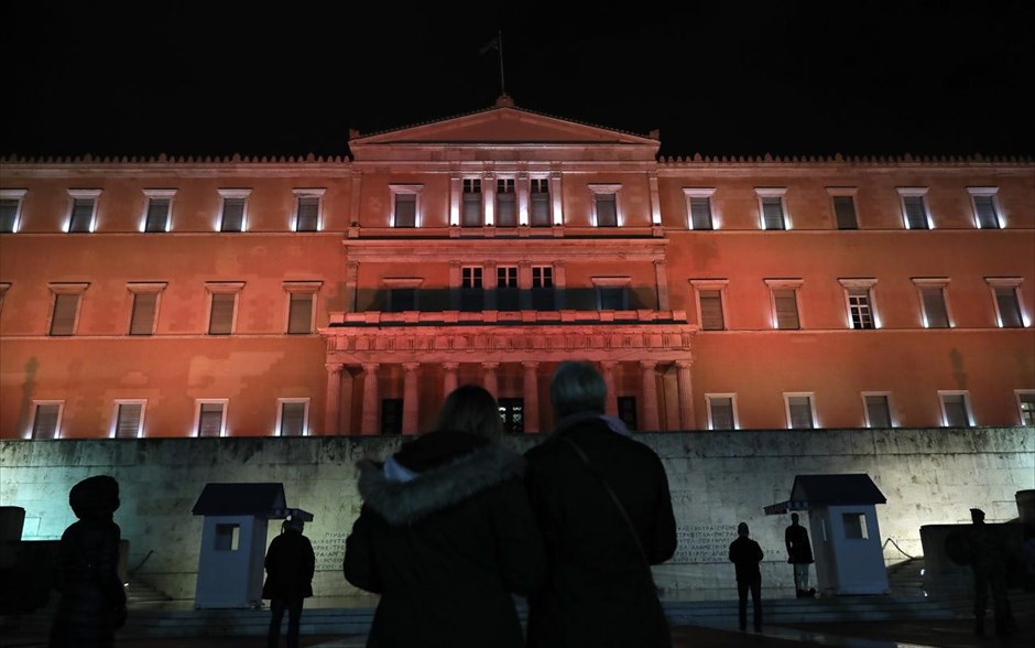 Στα κόκκινα η Βουλή. Κόσμος κοιτάζει το φωτισμό του κτιρίου της Βουλής που «ντύθηκε» στα κόκκινα για την παγκόσμια ημέρα για την εξάλειψη της βίας κατά των γυναικών. 