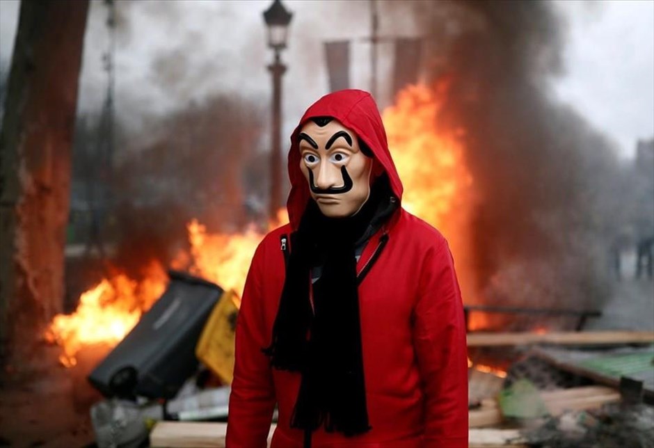 POY 2018. Οι κινητοποιήσεις των Γάλλων πολιτών, που διαμαρτύρονται για τις υψηλές τιμές των καυσίμων φορώντας τα χαρακτηριστικά κίτρινα γιλέκα, εξελίχθηκαν σε επεισόδια μεγάλης κλίμακας στην πρωτεύουσα του Παρισιού. Στη φωτογραφία διαδηλωτής φορώντας μάσκα απεικονίζεται με φόντο φλεγόμενα αντικείμενα στα Ηλύσια Πεδία.&nbsp;(26 Νοεμβρίου 2018).