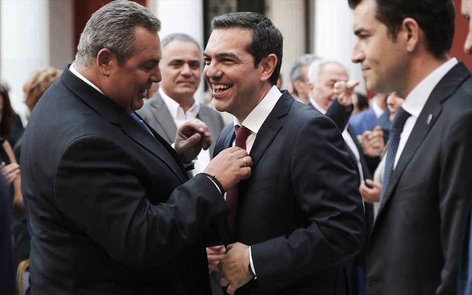 POY 2018. Ο υπουργός Εθνικής Άμυνας Πάνος Καμμένος περιποιείται την γραβάτα του&nbsp;πρωθυπουργού Αλέξη&nbsp;Τσίπρα, ο οποίος εμφανίστηκε&nbsp;για πρώτη φορά με γραβάτα&nbsp;στο Αίθριο του Ζαππείου Μεγάρου, όπου πραγματοποίησε ομιλία στις κοινοβουλευτικές ομάδες του ΣΥΡΙΖΑ και των ΑΝΕΛ μία ημέρα μετά τη συμφωνία στην οποία κατέληξε το Eurogroup (22 Ιουνίου 2018).&nbsp;