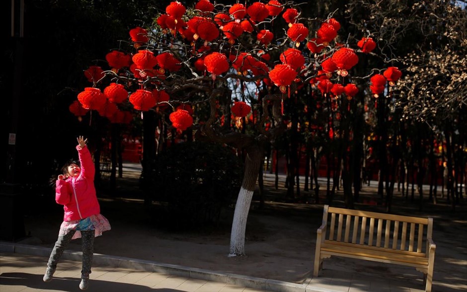 Εορταστικό κλίμα στην Κίνα. Ένα κοριτσάκι πηδάει για να φτάσει τον πρωτοχρονιάτικο στολισμό ενός δέντρου στο&nbsp;Ditan Park του Πεκίνου. Η&nbsp;κινεζική Πρωτοχρονιά θα γιορταστεί&nbsp;στις 5 Φεβρουαρίου.